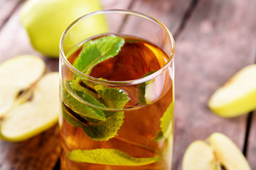 Glass of apple juice with fruits and fresh mint on table close up