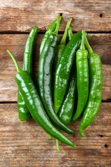 Green hot peppers on wooden table close up