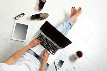 Top view of young woman sitting on floor with laptop
