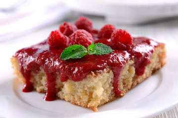 Fresh pie with raspberry jam in white saucer on wooden table, closeup