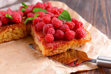 Fresh pie with raspberry on parchment on wooden table, closeup