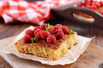 Fresh pie with raspberry on parchment on wooden table, closeup