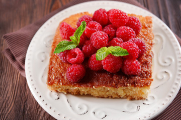 Fresh pie with raspberry in white saucer on wooden table, closeup