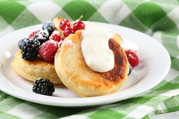 Fritters of cottage cheese with berries in plate, closeup
