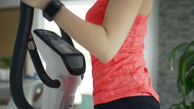 Young woman exercising on elliptical machine in the gym
