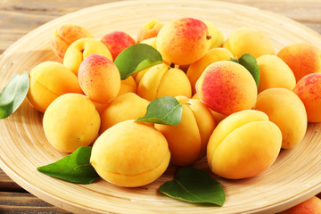 Ripe apricots on wooden plate, closeup
