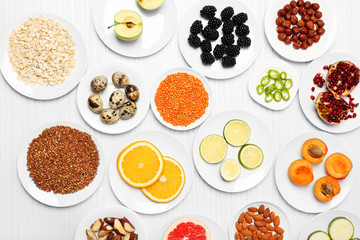 Different products on saucers on wooden table, top view