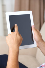 Male hand holding PC tablet on home interior background