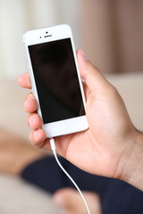 Music smartphone in male hand, on home interior background