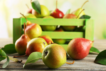 Fresh pears in crate on wooden table on blurred background