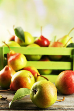 Fresh pears in crate on wooden table on blurred background