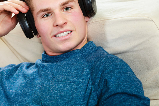 Young man with headphones lying on couch