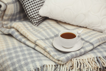 Cup of coffee on sofa in living room