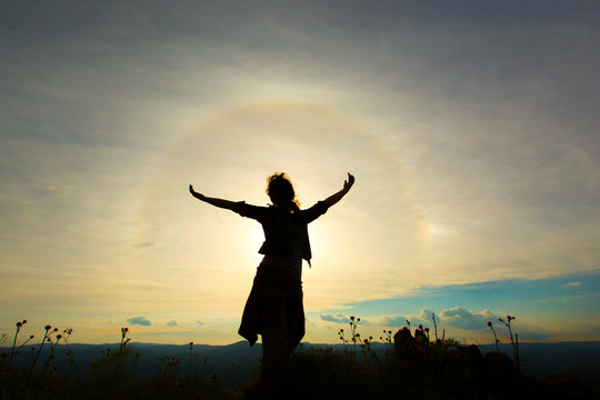 Young women joyfully jumping with sunbow in background