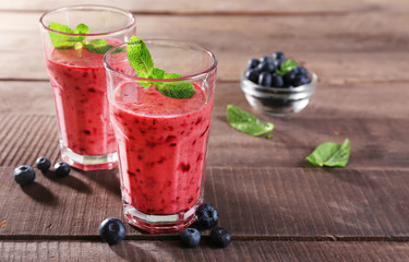 Glasses of berry smoothie on wooden background
