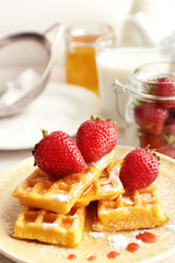 Sweet homemade waffles with fresh strawberries on plate, on light background