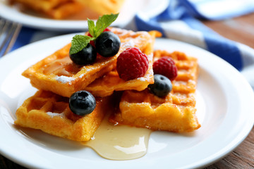 Sweet homemade waffles with forest berries and sauce on table background