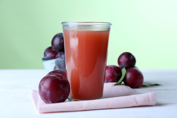 Delicious plum juice with fruits on green background