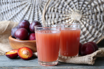 Delicious plum juice with fruits on wicker background