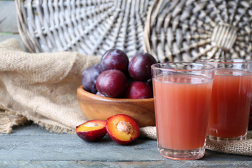 Delicious plum juice with fruits on wicker background