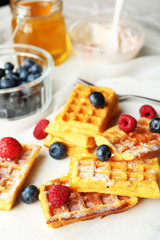 Sweet homemade waffles on tray, on light background