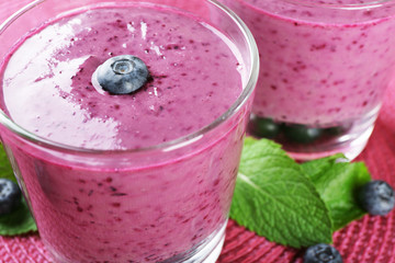 Glasses of blueberry smoothie on pink mat, closeup