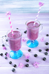 Glasses of blueberry smoothie on wooden table, closeup