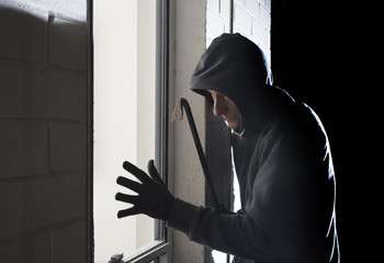 Burglar with crowbar next to window