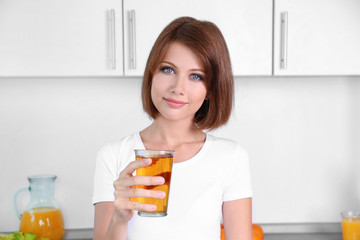 Young beautiful woman showing glass of apple juice