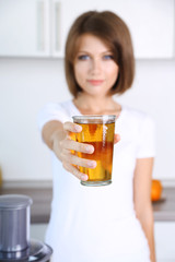 Young beautiful woman showing glass of apple juice