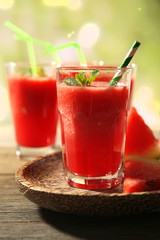 Glasses of watermelon juice on wooden table on blurred background