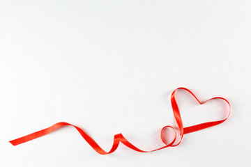 Red heart ribbon on light grey textured background