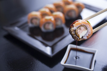 Sushi roll with cream cheese and fried salmon. Topped with raw s