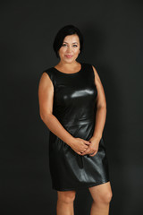 Portrait of pretty woman in black leather dress on dark background