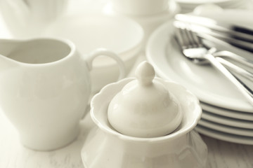 Set of white ceramics dishes on wooden table, closeup