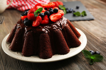 Delicious chocolate cake with berries in plate on table, closeup
