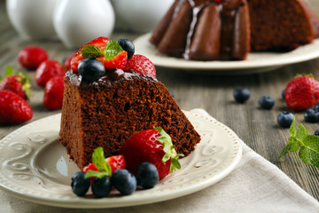 Piece of chocolate cake with berries in plate on table, closeup