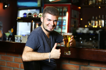 Young man drinking beer in bar