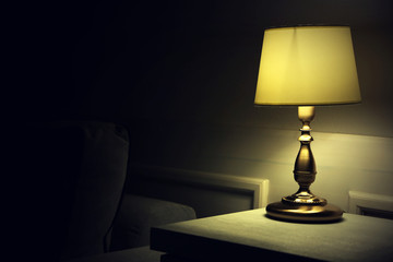 Old fashion table lamp on nightstand on wall background