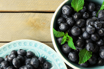 Cup and plate with fresh blueberries on wooden table close up