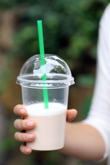 Woman holding plastic cup of milkshake  close-up, outdoors