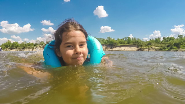 the girl child is learning to swim in the river lifejacket