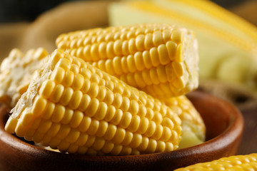 Ripe corn in bowl on wooden background