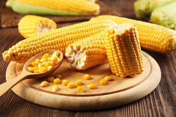 Ripe corn on cutting board on wooden background
