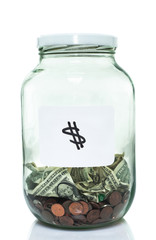 Glass jar with with a white dollar sign label and some money in