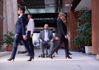 business man sitting in office chair, people group  passing by