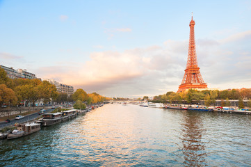Eiffel tower with an orange color at sunset and river seine in Paris, France