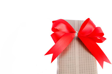 Wrapped gift box with red ribbon bow isolated on white background.