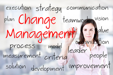 Young business woman writing change management concept. Office background.