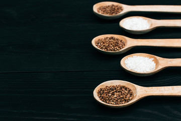 Obraz na płótnie Canvas rice and buckwheat groats in the wooden spoon on the black table